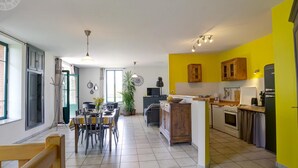 Een moderne keuken met gele wanden, een eethoek met een grote tafel en een zichtbare oven.