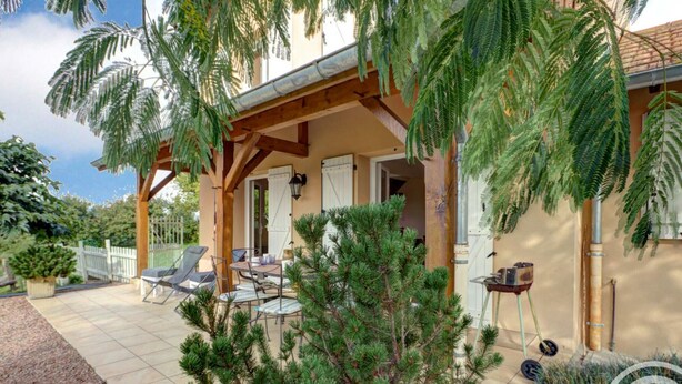 A covered outdoor patio with a table and chairs, surrounded by greenery and a small tree. - Cottage in Saint-Forgeux-Lespinasse with Terrace and Pets Allowed (Saint-Forgeux-Lespinasse)