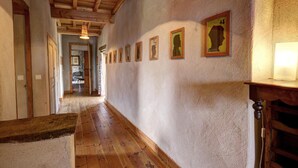 A hallway with wooden flooring, a stone wall, and framed pictures on the wall.