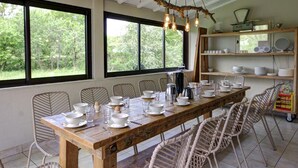 A dining area with a long wooden table set for a meal, surrounded by wicker chairs. - Large house with heated private pool and pets allowed (Vivans)