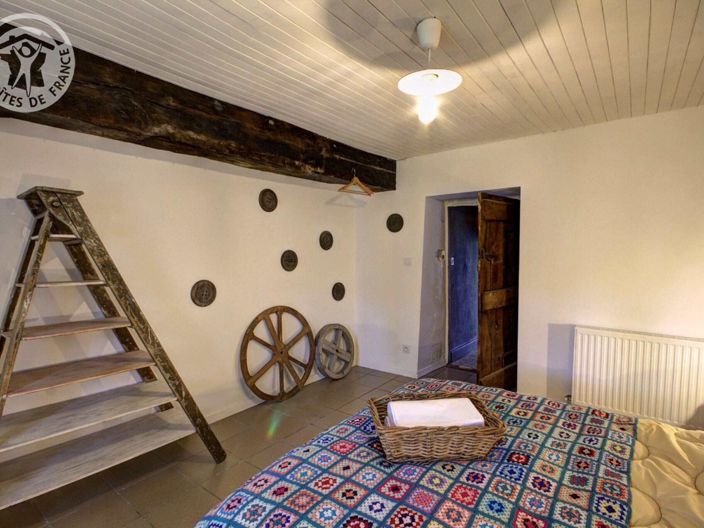 Une pièce avec un lit, une échelle, un panier et une porte.