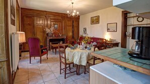 A cozy dining room with wooden furniture, a chandelier, and a tiled floor.