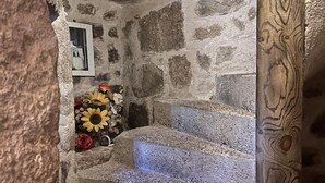 A stone staircase with a rustic interior, a framed picture on the wall, and a floral arrangement at the bottom.