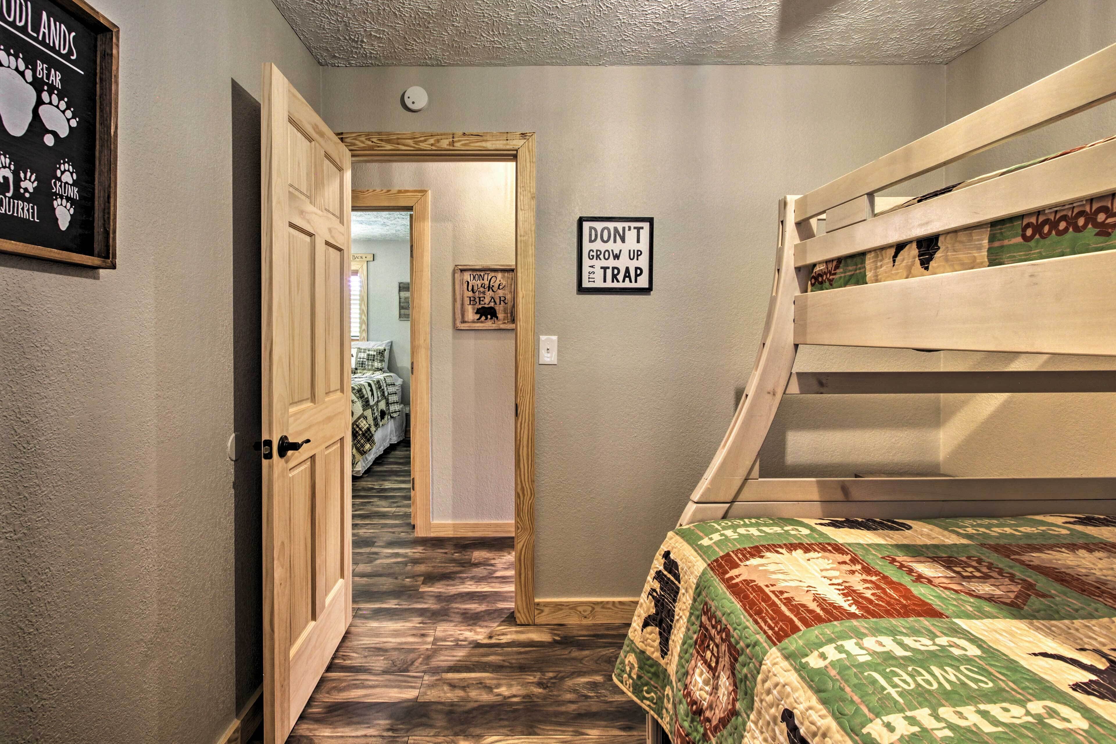 A room with bunk beds, a hallway leading to another room, and a sign on the wall.
