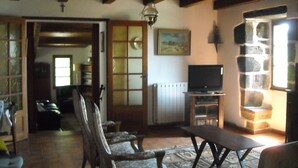 A cozy living room with a television, wooden furniture, a stone wall, and a painting on the wall. - Comfortable house with swimming pool in the ardèchoise mountain (Saint-Joseph-des-Bancs)