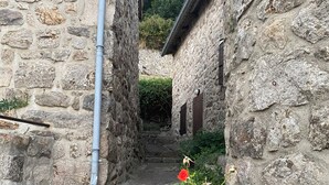 A narrow stone alleyway with a rustic stone building on one side and a metal pipe running along the wall. - Comfortable house with swimming pool in the ardèchoise mountain (Saint-Joseph-des-Bancs)
