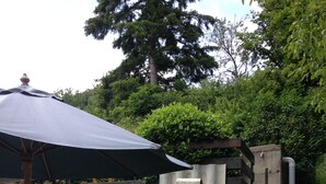 An outdoor patio with a stone wall, a pizza oven, a table with chairs, and an umbrella. - Comfortable house with swimming pool in the ardèchoise mountain (Saint-Joseph-des-Bancs)