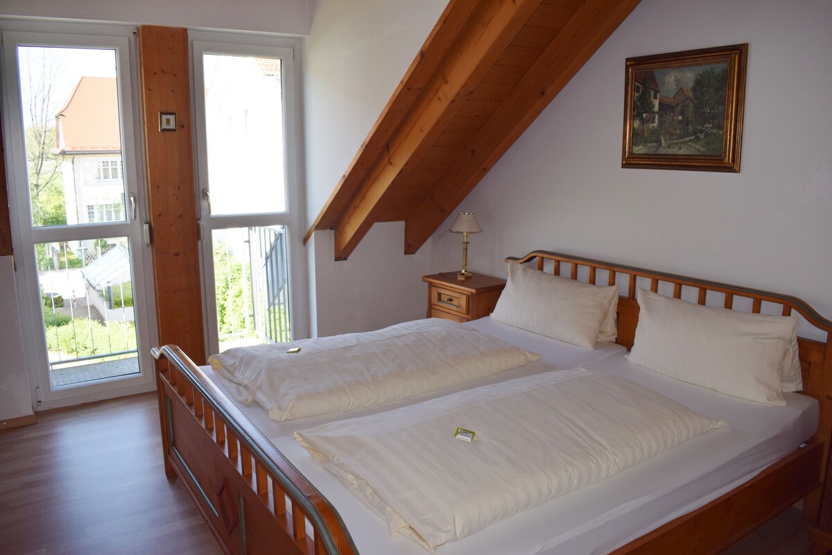 A bedroom with two beds, a wooden ceiling, a painting, and a nightstand.