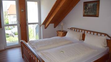 A bedroom with two beds, a wooden ceiling, a painting, and a nightstand.