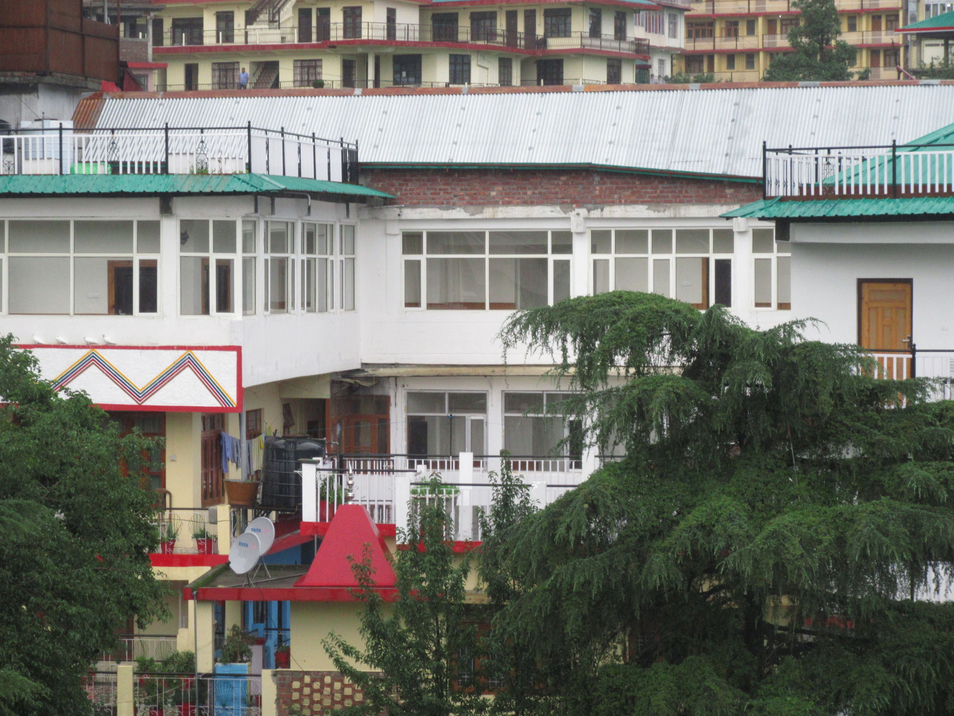 A multi-story building with balconies, a red roof, and satellite dishes.