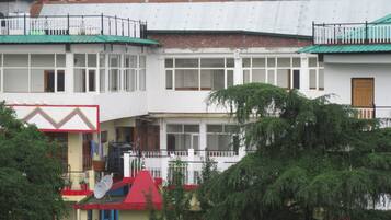 A multi-story building with balconies, a red roof, and satellite dishes.
