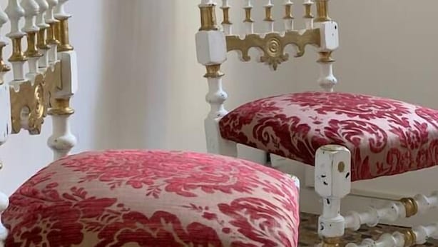 Two ornate white chairs with red cushions and gold accents, positioned in a room with a white wall and a framed picture above. - Rosso apartment, first floor (Unknown)