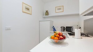 A modern kitchen with white cabinetry, a microwave, a stove, and a fruit bowl on the counter. - Rosso apartment, first floor (Unknown)