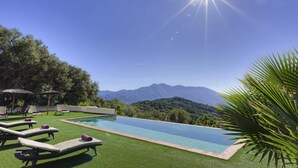 A swimming pool with a view of mountains, surrounded by lounge chairs and greenery. - Villa with infinity pool (Gaucín)