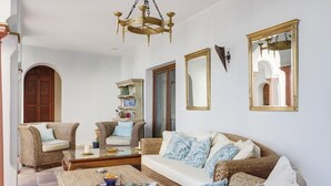 A living room with wicker furniture, a glass coffee table, and a chandelier. - Villa with infinity pool (Gaucín)