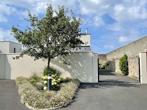 A modern building with a tree and flower garden in front.