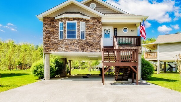 A two-story house with a stone facade, a balcony, and an American flag.