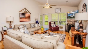 A living room with a sofa, coffee table, and a television displaying a seven-day weather forecast.