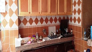 Een keuken met houten kastjes, een granieten aanrechtblad en een betegelde spatwand.