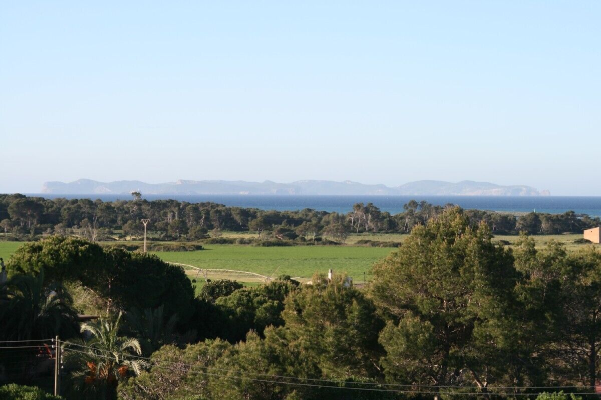 A coastal landscape with a view of the sea and distant mountains.