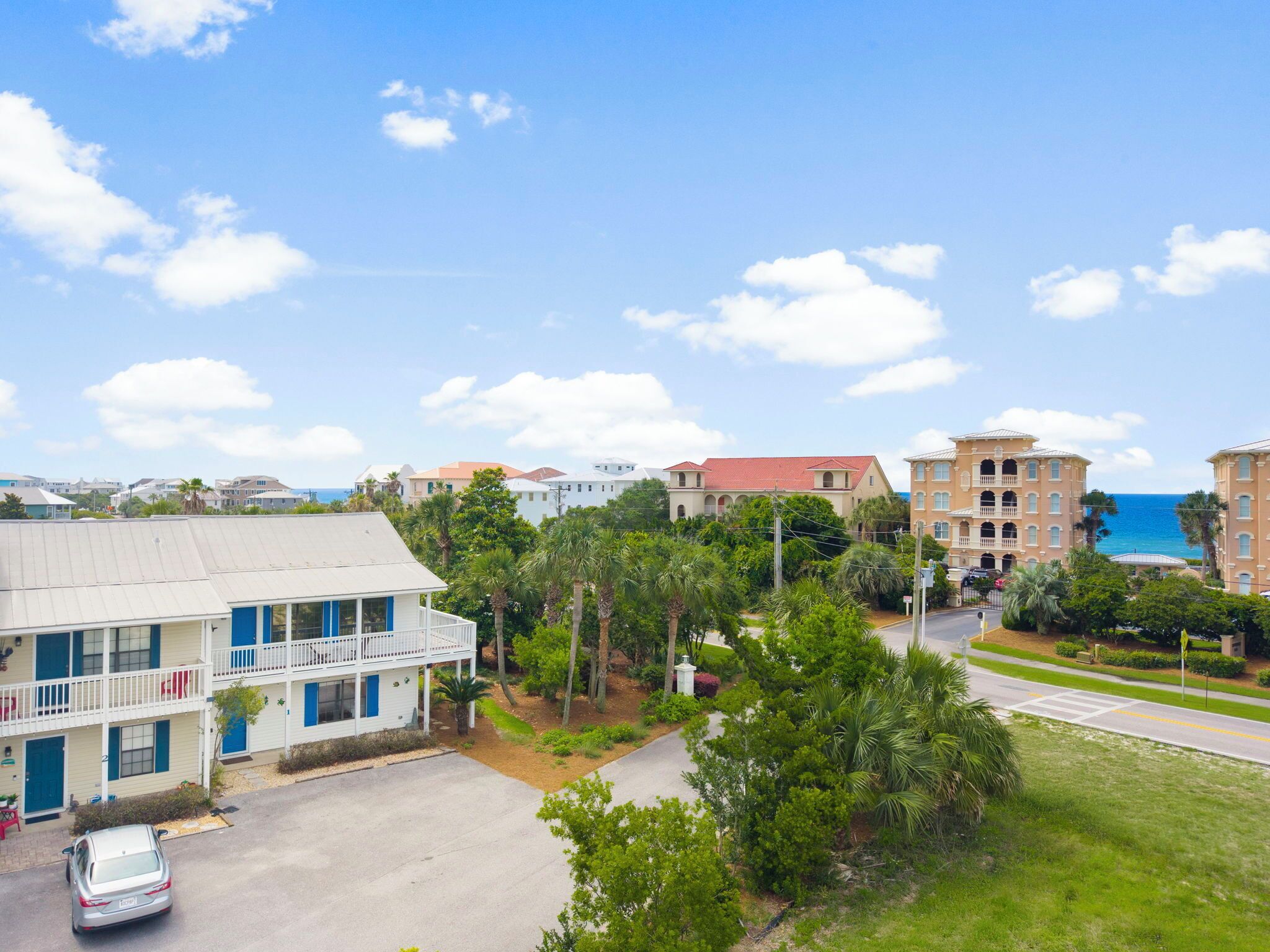 A coastal hotel with a two-story building, a parking area, and a view of the ocean.