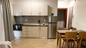 A compact kitchen with a dining area, wooden flooring, and a small table with chairs. - Elata-apartments (Thasos)