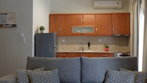 A compact kitchen with wooden cabinets, a built-in microwave, and a sink. - Elata-apartments (Thasos)