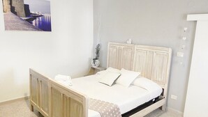 Un dormitorio con cama, mesita de noche e imagen colgada en la pared.