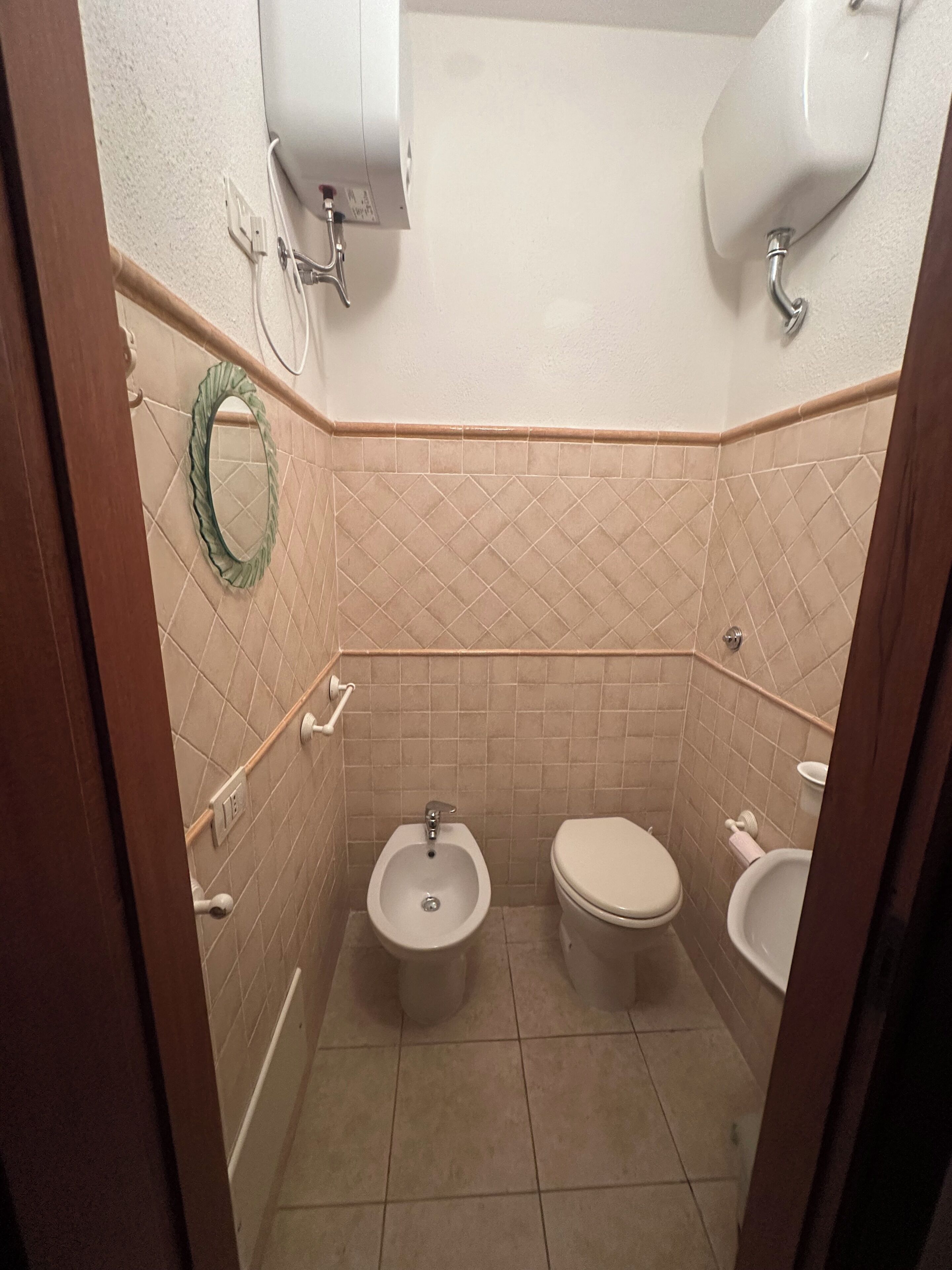 A small bathroom with a bidet, toilet, and sink.