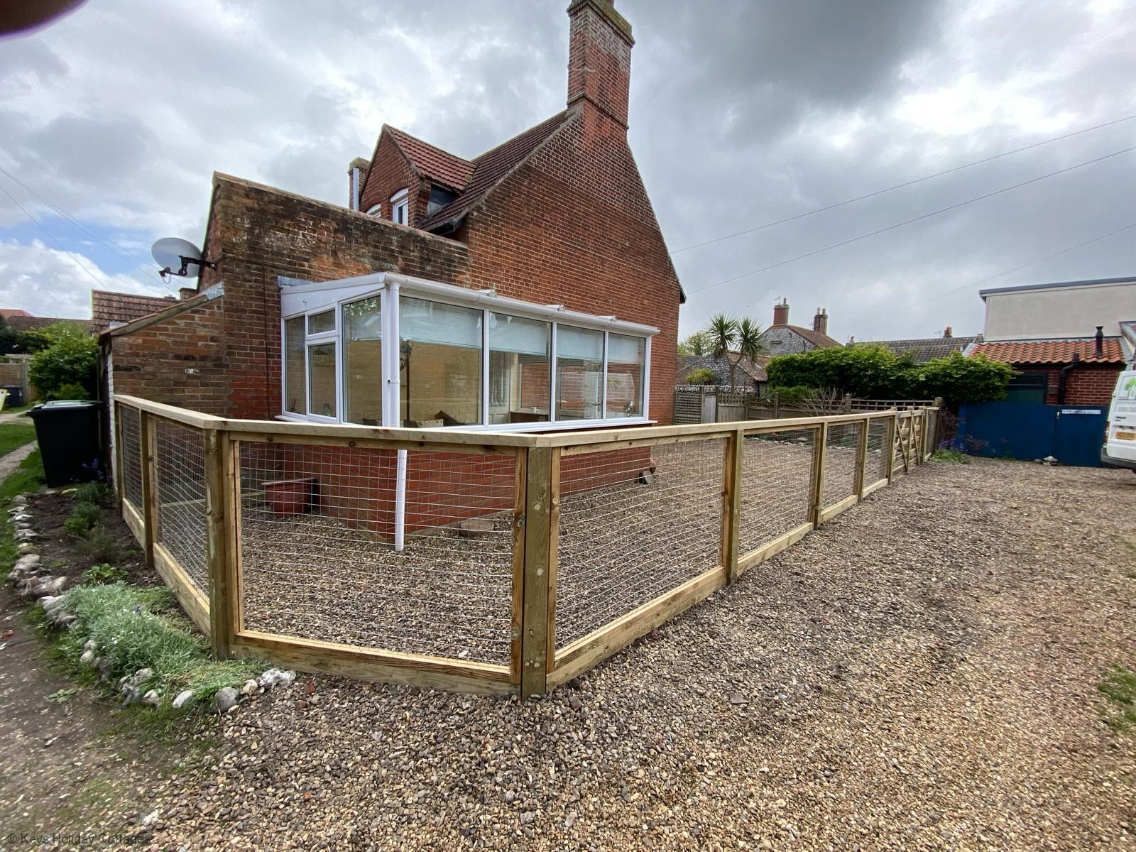 A house with a fenced garden area and a brick chimney.