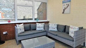 A cozy living room with a grey sectional sofa, a glass coffee table, and patterned cushions. - 1 Orchard Cottages -  a cottage that sleeps 5 guests  in 2 bedrooms (Cromer)