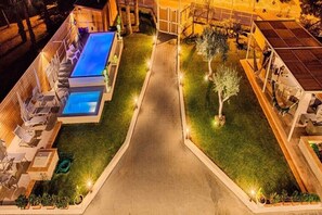 Uma área de piscina no terraço, com vista clara do céu, rodeada por espreguiçadeiras e um caminho que leva à piscina.