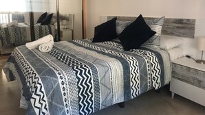 Un dormitorio moderno con una cama grande, una mesita de noche, un espejo y un buró.