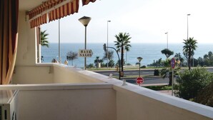 Un balcón con vista al mar, una señal de stop y un letrero de salón de belleza.