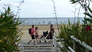 Ein Uferweg, der zum Strand führt, mit Blick auf das Meer und Boote.