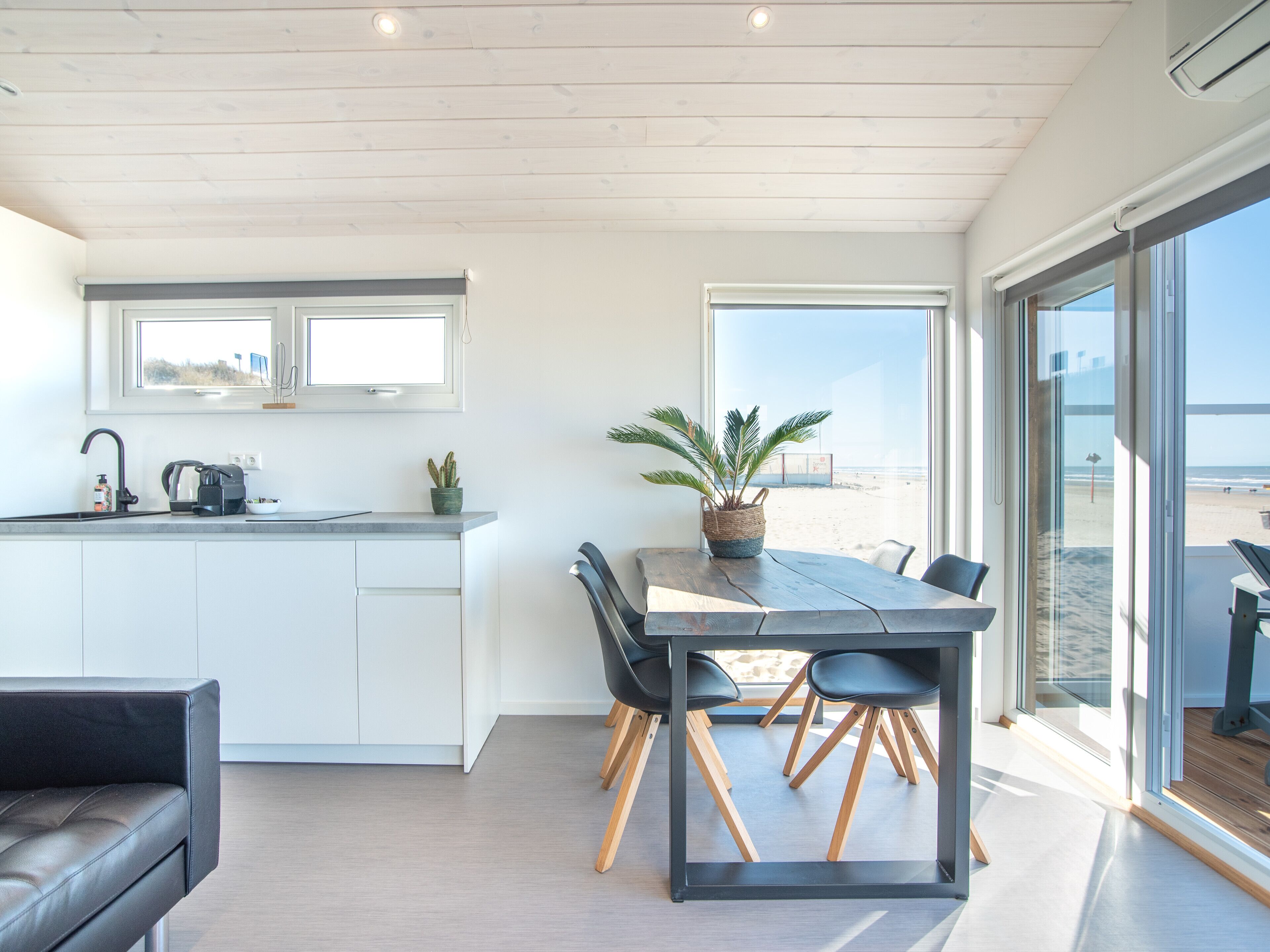 Una cucina moderna con zona pranzo, ampie finestre e vista sulla spiaggia.