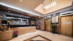 A hotel reception area with a reception desk, information and reservation signs, an elevator, and a decorative floor pattern. - Incheon Prince Tourist Hotel (Incheon)