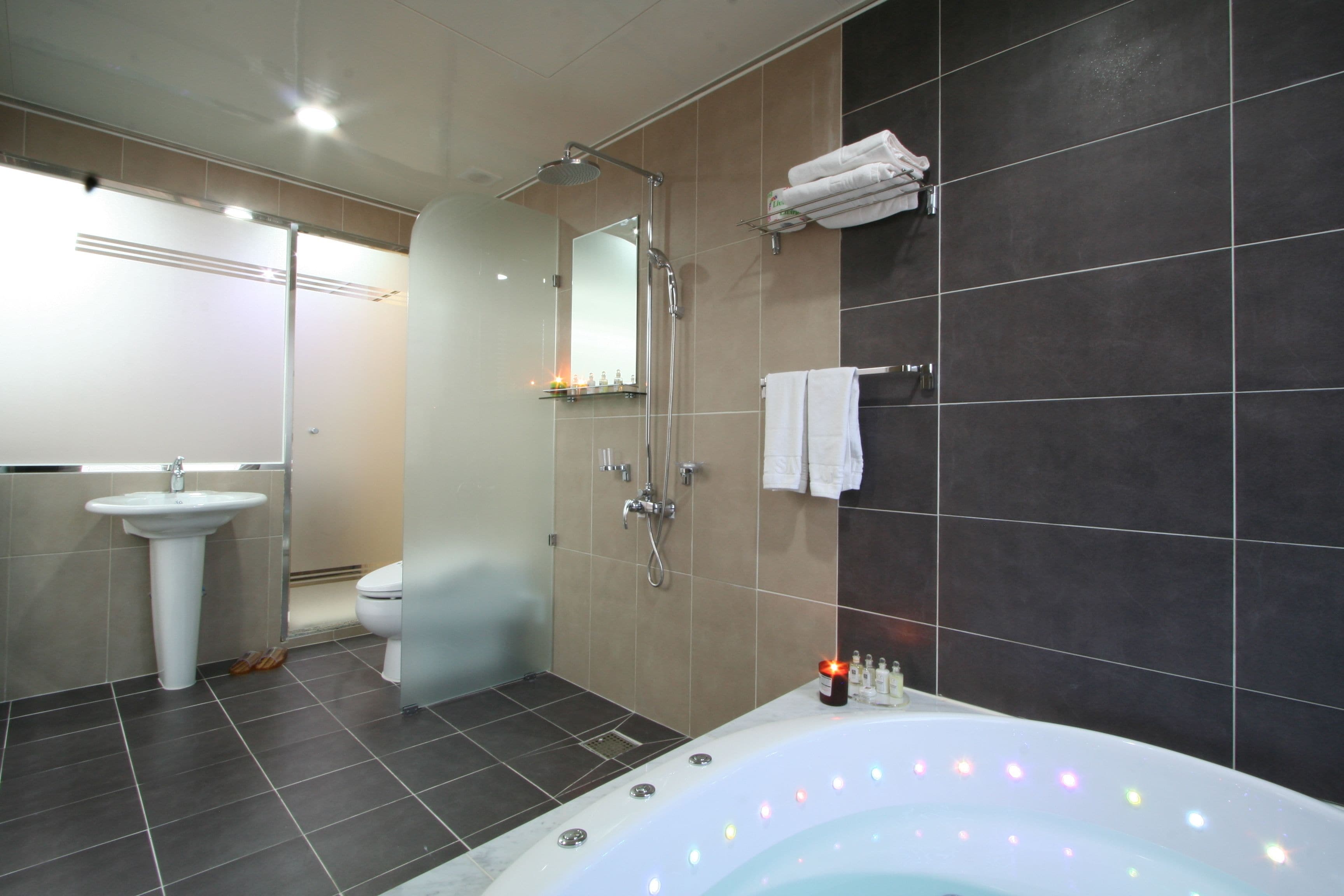 A modern bathroom with a bathtub, shower, sink, and toilet.