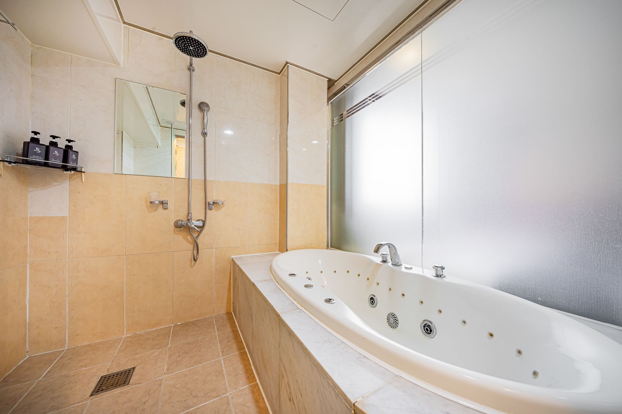 A modern bathroom with a large bathtub, a showerhead, and a mirror.