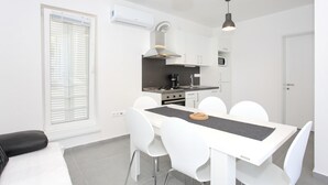 Une cuisine moderne avec des meubles blancs, un îlot central et des luminaires suspendus.