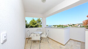 Un balcon doté d’un sol en pierre, de murs blancs et offrant une vue sur la ville.