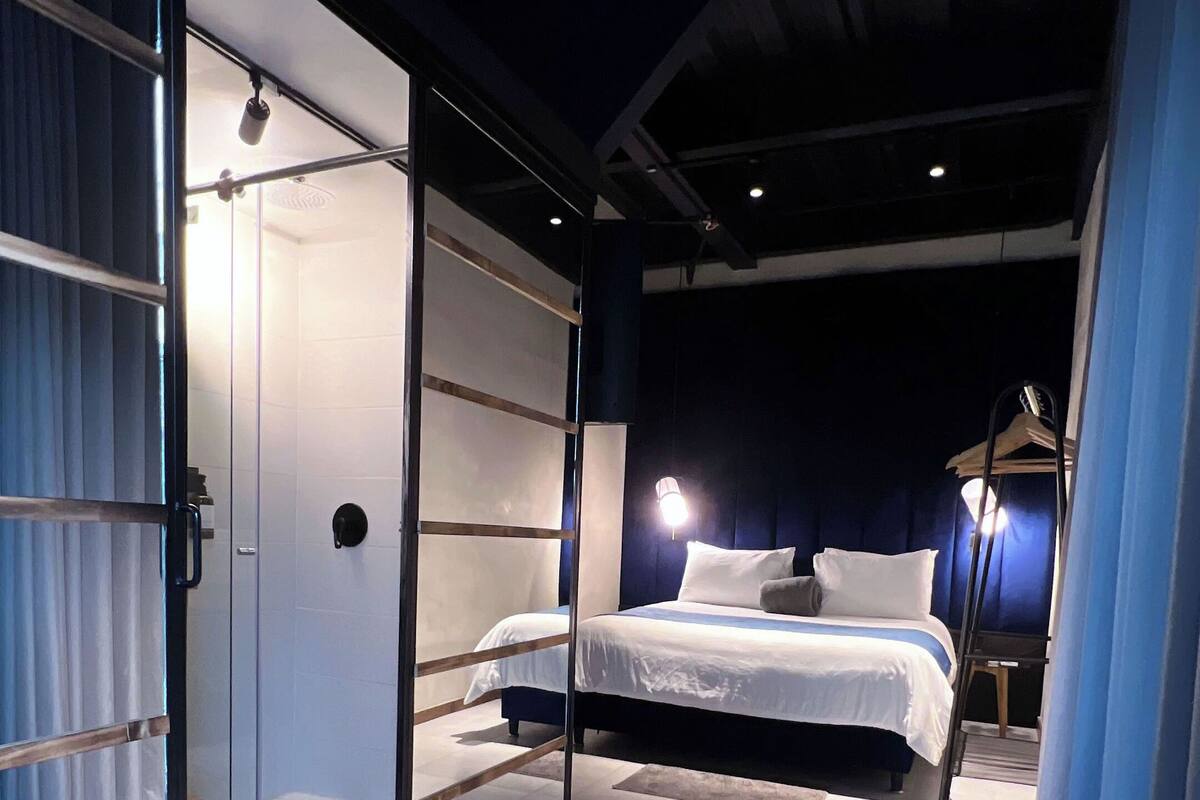 Ein modernes Schlafzimmer mit Glastrennwand, einem Bett und einem Nachttisch.
