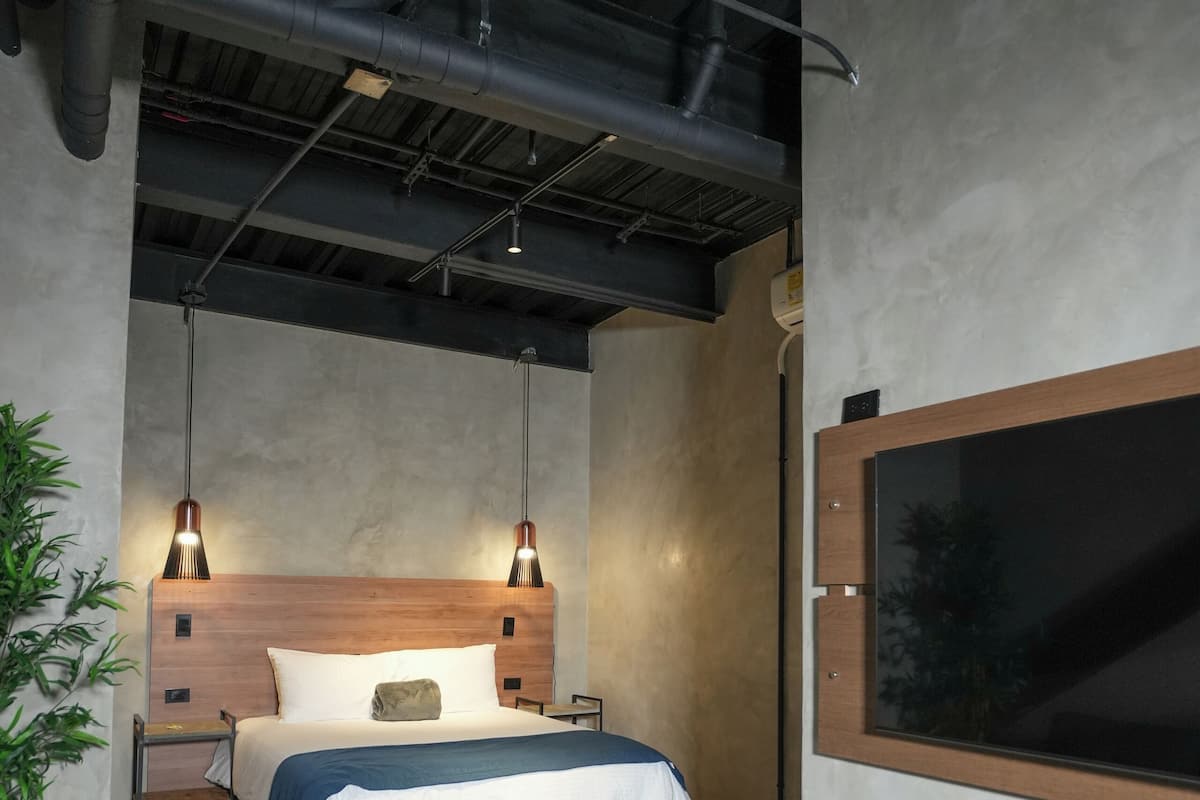 Ein modernes Schlafzimmer mit einem großen Bett, Nachttischen, einem Fernseher und einer Bank.