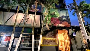 A hotel with a modern facade, palm trees, and a large mural. - Hotel Lleras Park Concept (Medellín)