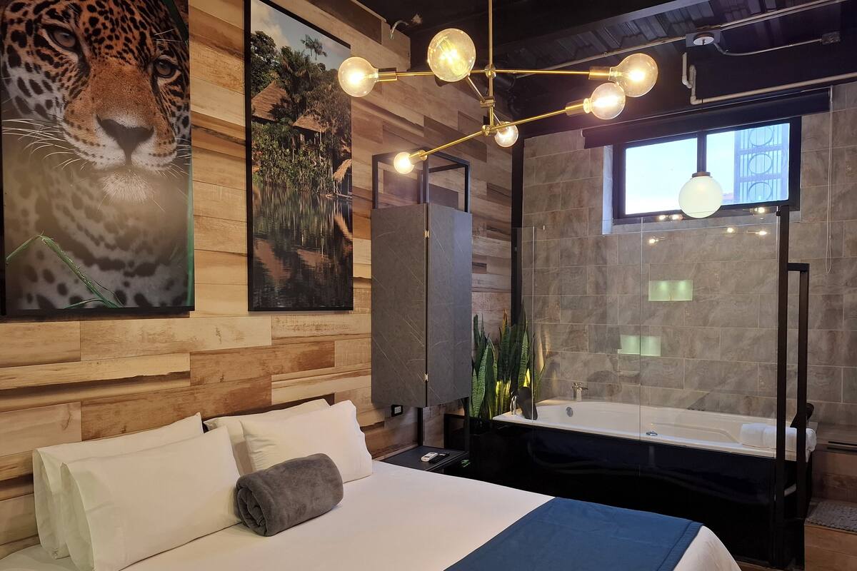 Ein modernes Hotelzimmer mit einem großen Bett, einer Badewanne und einem großen Fenster.