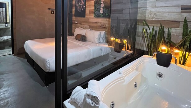 A modern hotel room with a large bathtub, a separate bed, and a glass partition. - Hotel Lleras Park Concept (Medellín)