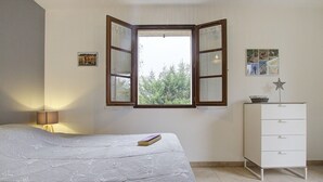 A bedroom with a bed, a window, a dresser, and a lamp. - Gîte du Héron Gris (BOULIGNEUX)