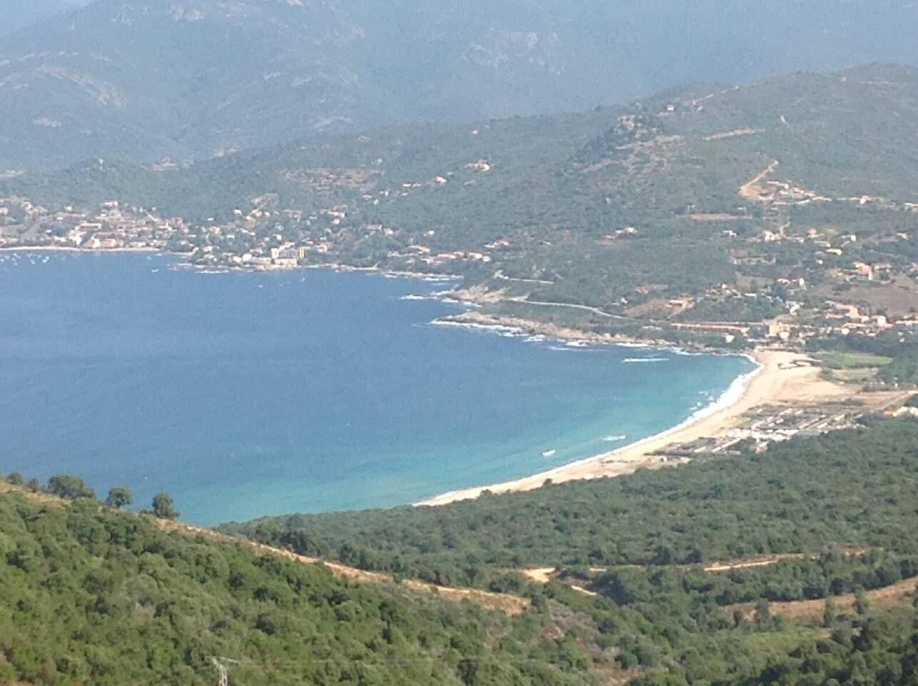 Un paisaje costero con una playa y colinas circundantes.