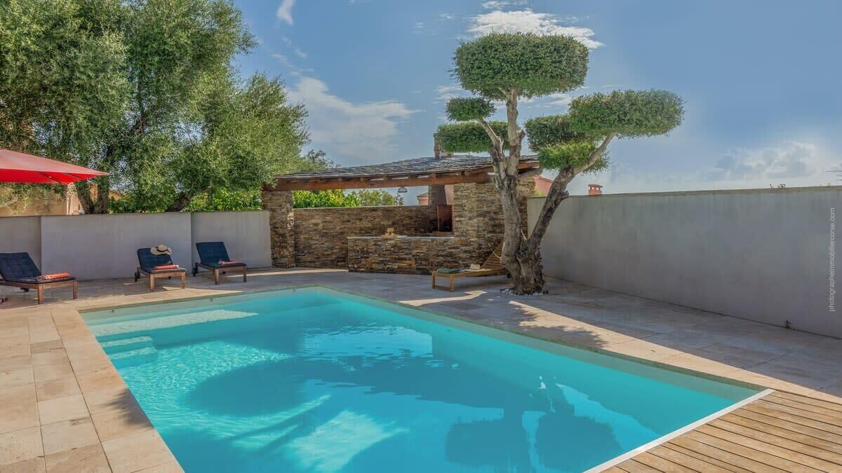 Une piscine avec des chaises longues et un mur en pierre.