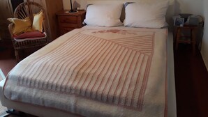 Ein Schlafzimmer mit Bett, Sessel, Nachttisch und Lampe.